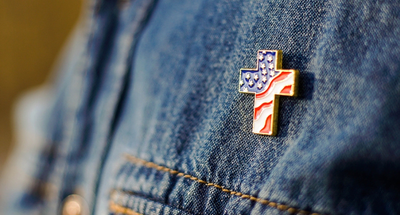 Cross pin with American flag colors pinned on jacket.
