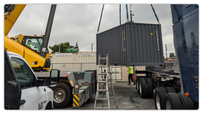 The container is slowly lifted and rotated to be aligned with the truck.
