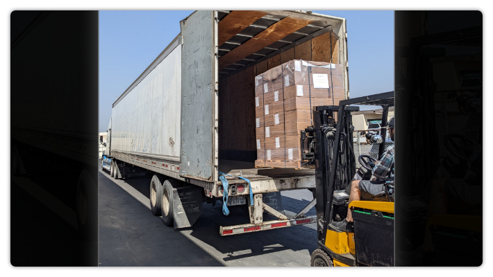 Pallets of tracts being loaded into semi-truck trailer.